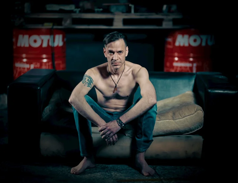 topless man in blue shorts sitting on black couch